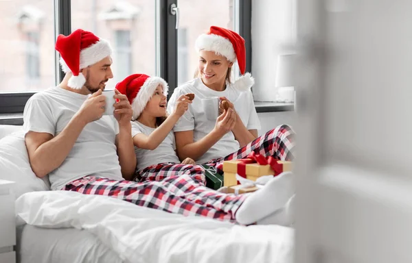 Happy family eating coookies in bed on christmas — Stock Photo, Image