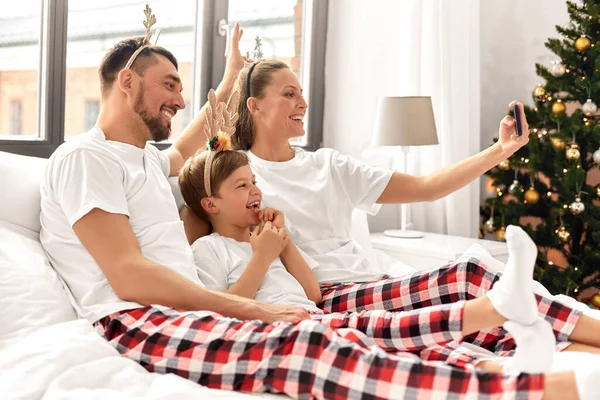 穿睡衣的家庭在床上吃圣诞节的自助餐 — 图库照片