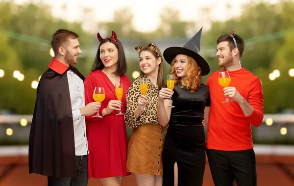 Glada vänner i halloween kostymer över grå — Stockfoto