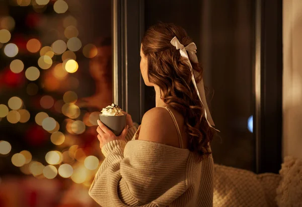 Женщина держит кружку со взбитыми сливками на Рождество — стоковое фото