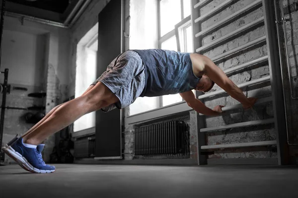 Muž cvičení na gymnastika zeď tyče v tělocvičně — Stock fotografie