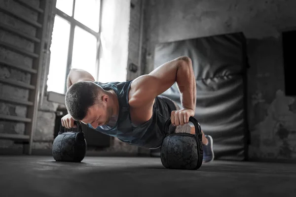 Joven haciendo flexiones kettlebell en el gimnasio —  Fotos de Stock