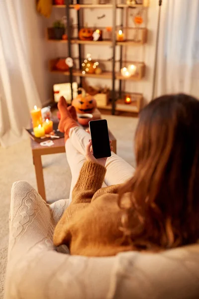 Жінка використовує смартфон вдома на Хеллоуїн — стокове фото