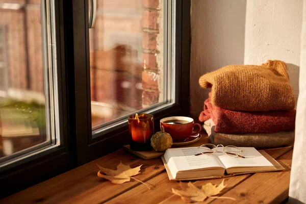 Boek, koffie en kaars op vensterbank in de herfst — Stockfoto