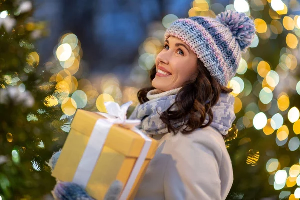 Gelukkig vrouw met kerstcadeau over lichten — Stockfoto