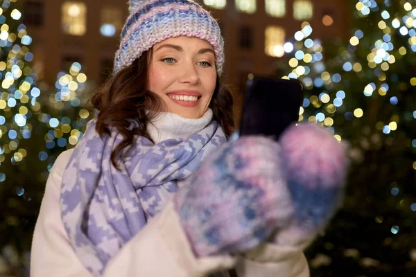 Lycklig kvinna med smartphone i jul stad — Stockfoto