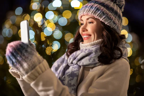 Gelukkig vrouw met smartphone in kerst stad — Stockfoto