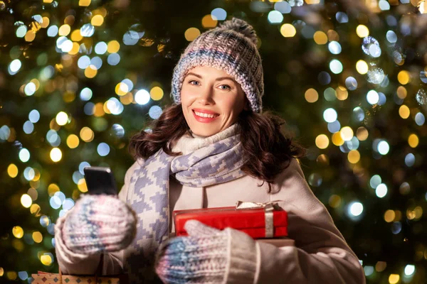 Femme heureuse avec cadeaux de Noël et smartphone — Photo