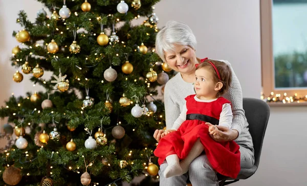 Grootmoeder en baby meisje met bij kerst boom — Stockfoto