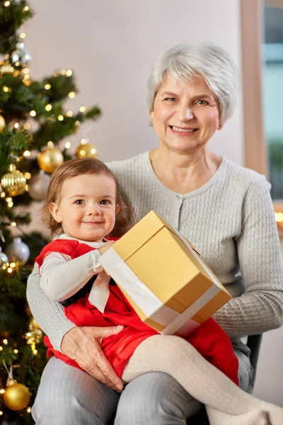 Mormor och liten flicka med julklapp — Stockfoto