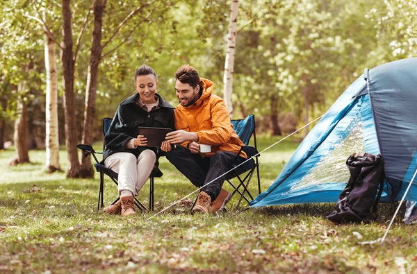 Couple with tablet pc drinking tea at tent camp — Stock Photo, Image