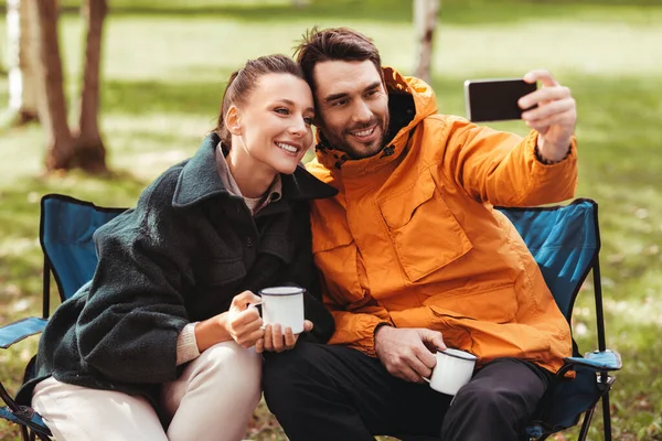 Pár pije čaj a brát selfie na táboře stan — Stock fotografie