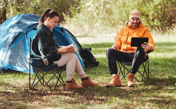 Casal com tablet pc e livro no acampamento tenda — Fotografia de Stock