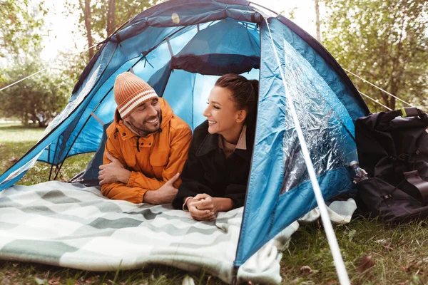 Casal feliz deitado dentro da tenda no acampamento — Fotografia de Stock