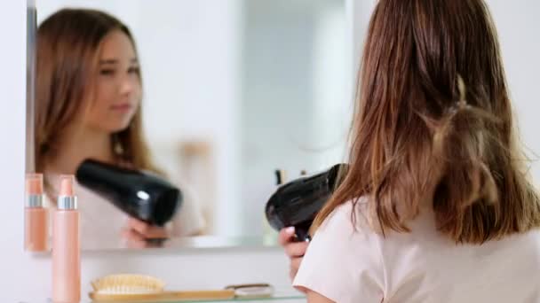 Teenage girl with hair dryer at bathroom — Stock Video