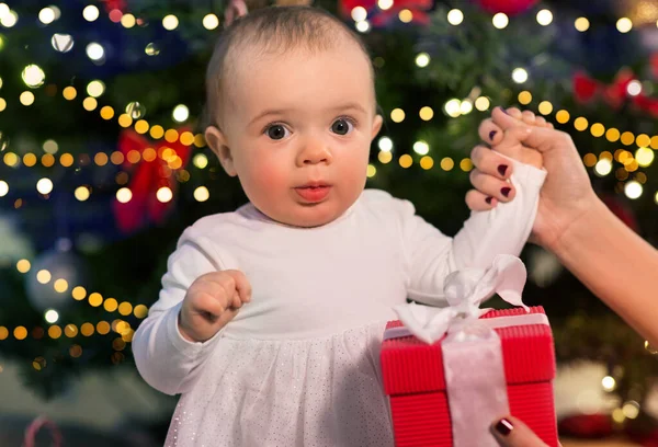 Baby girl with gift over christmas tree at home — Stock Photo, Image