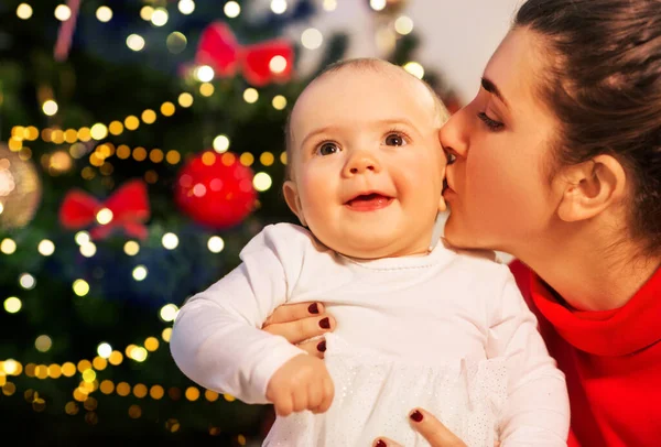 Mère embrasser bébé fille sur arbre de Noël — Photo