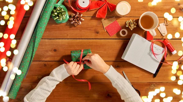 Hände packen Weihnachtsgeschenk und binden Band — Stockfoto