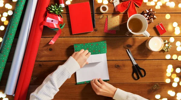 Руки заворачивая рождественский подарок в бумагу дома — стоковое фото