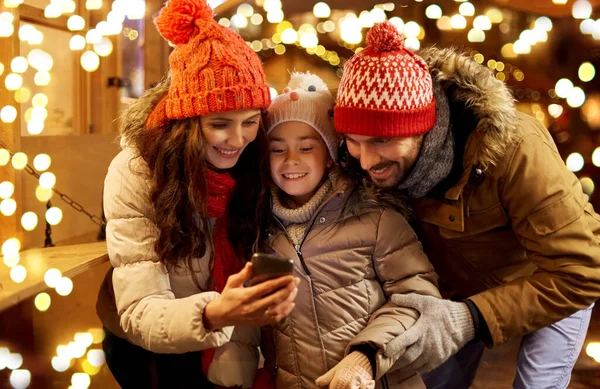 Щаслива сім'я зі смартфоном на різдвяному ринку Стокова Картинка