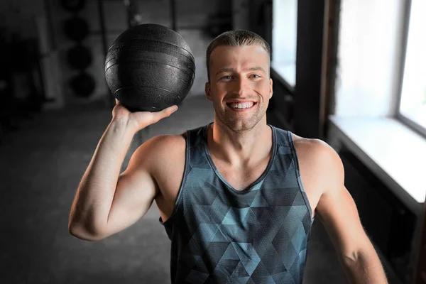 Glücklich lächelnder junger Mann mit Medizinball in Turnhalle — Stockfoto