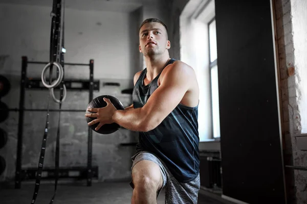 Jeune homme faisant de l'exercice avec la médecine balle dans la salle de gym — Photo