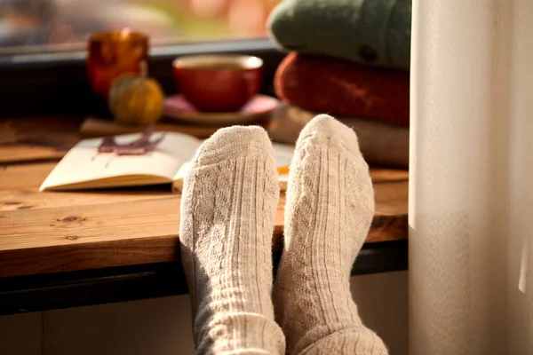 Pies en calcetines calientes en el alféizar de la ventana en casa en otoño —  Fotos de Stock