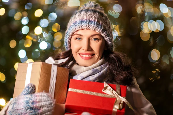 Gelukkig vrouw met kerst geschenken over lichten — Stockfoto