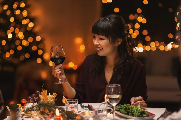 Счастливая азиатка пьет вино на рождественской вечеринке — стоковое фото