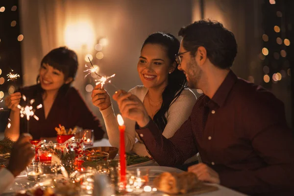 Amigos felices con bengalas en la cena de Navidad — Foto de Stock