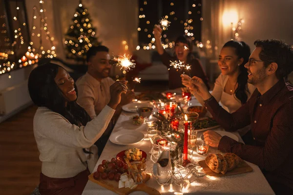 Amigos felices con bengalas en la cena de Navidad — Foto de Stock