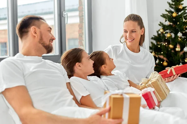 Happy family with christmas gifts in bed at home — Stock Photo, Image