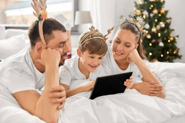 Familia con la tableta PC en la cama en la mañana de Navidad — Foto de Stock