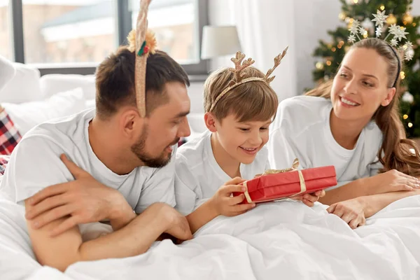 Οικογένεια με δώρο Χριστουγέννων στο κρεβάτι το πρωί — Φωτογραφία Αρχείου