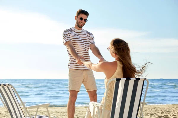 Felice coppia seduta in sedie pieghevoli sulla spiaggia — Foto Stock