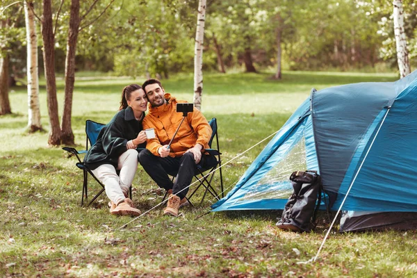 Casal beber chá e tomar selfie no acampamento da barraca — Fotografia de Stock