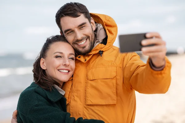 Para ze smartfonem na jesiennej plaży — Zdjęcie stockowe