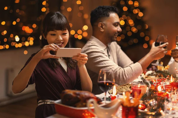 크리스마스 저녁 식사 때 음식 사진을 찍는 행복 한 여성 — 스톡 사진