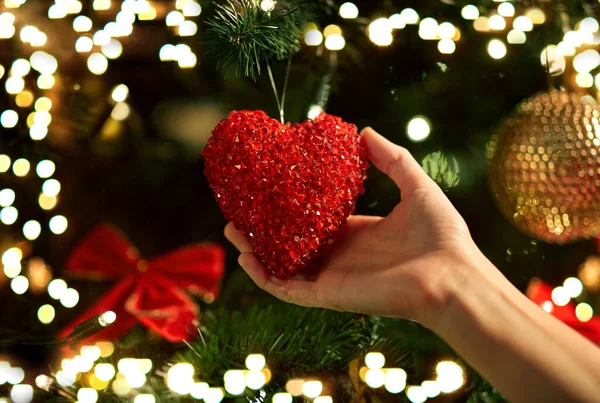 用红心装饰圣诞树的手 — 图库照片