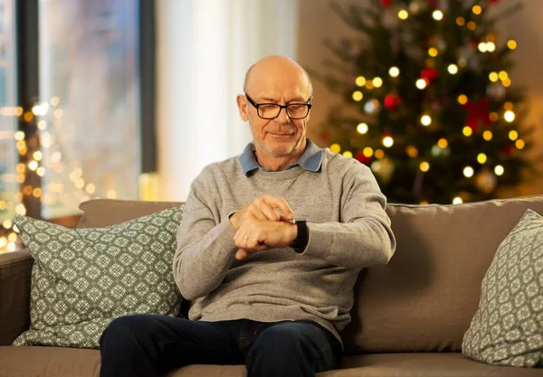 Ηλικιωμένος άνδρας που κοιτάζει το ρολόι χειρός τα Χριστούγεννα — Φωτογραφία Αρχείου