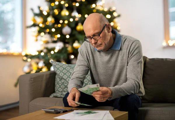 Hombre mayor contando dinero en casa en Navidad — Foto de Stock