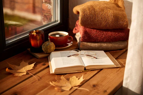 Boek, koffie en kaars op vensterbank in de herfst — Stockfoto