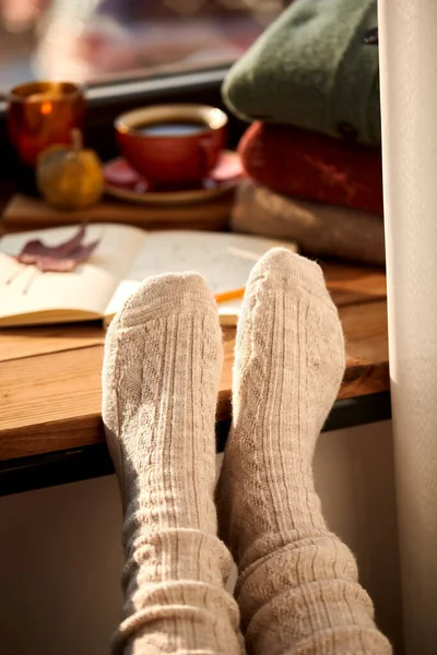 Pies en calcetines calientes en el alféizar de la ventana en casa en otoño —  Fotos de Stock