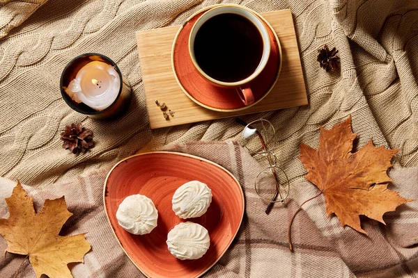 Cup of coffee, autumn leaves and candle in bed — Stock Photo, Image