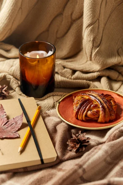 Дневник, карандаш, булочка с корицей и свечи осенью — стоковое фото