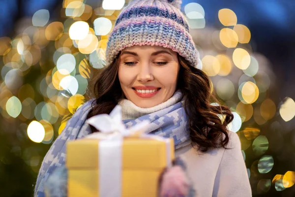 Mulher feliz com presente de Natal sobre luzes — Fotografia de Stock