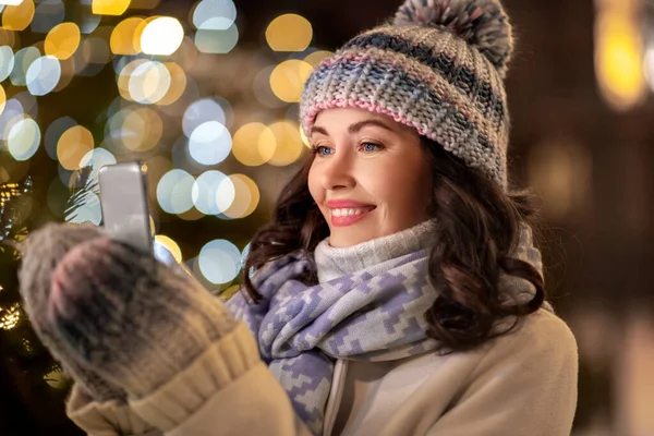 Lycklig kvinna med smartphone i jul stad — Stockfoto