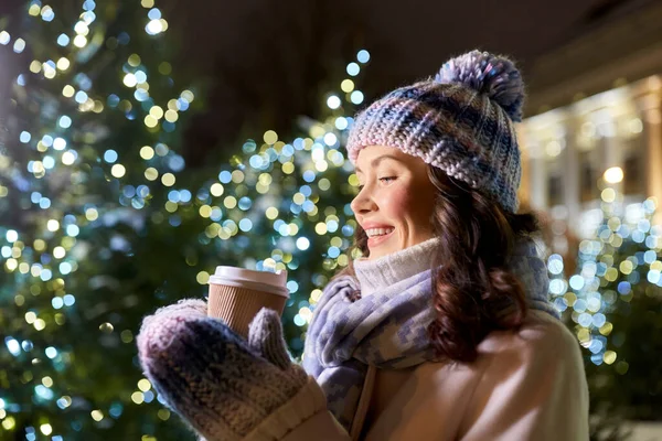 Gelukkig vrouw drinken koffie over kerstverlichting — Stockfoto