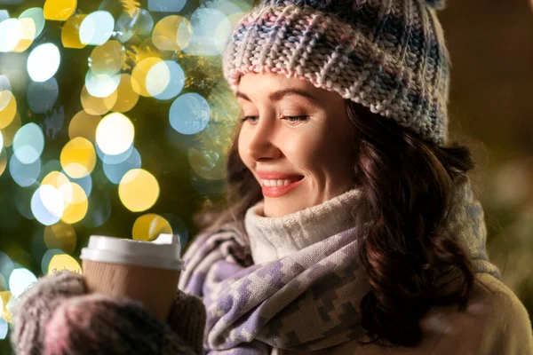 Щаслива жінка п'є каву над різдвяними вогнями — стокове фото