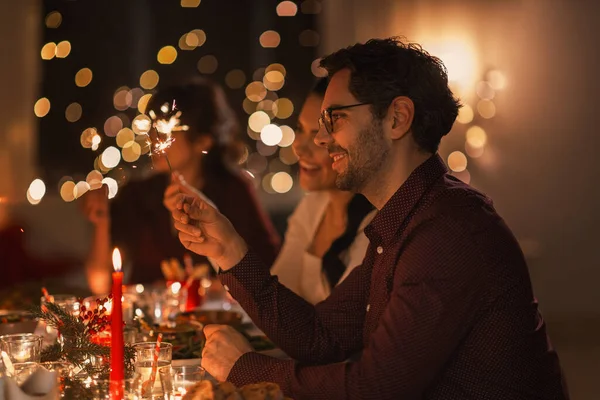 Amigos felizes com faíscas no jantar de Natal — Fotografia de Stock